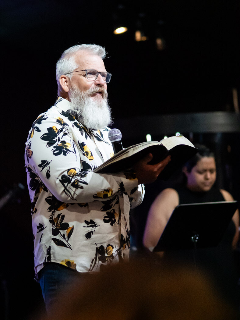 Pastor preaching from an open Bible at Overflow Worship Center